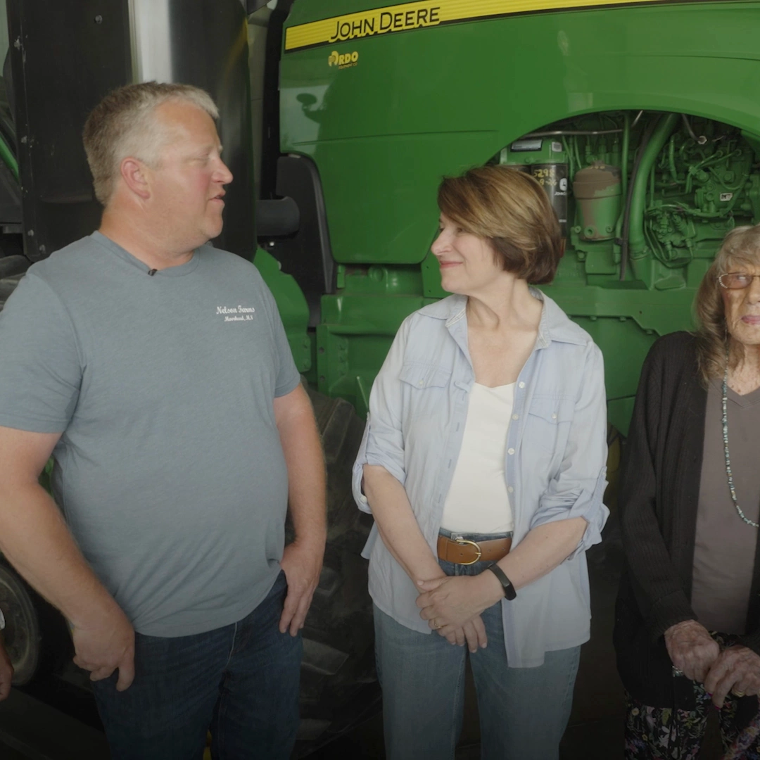 Amy Klobuchar talking with a farmer at the Nelson family farm in Moorhead